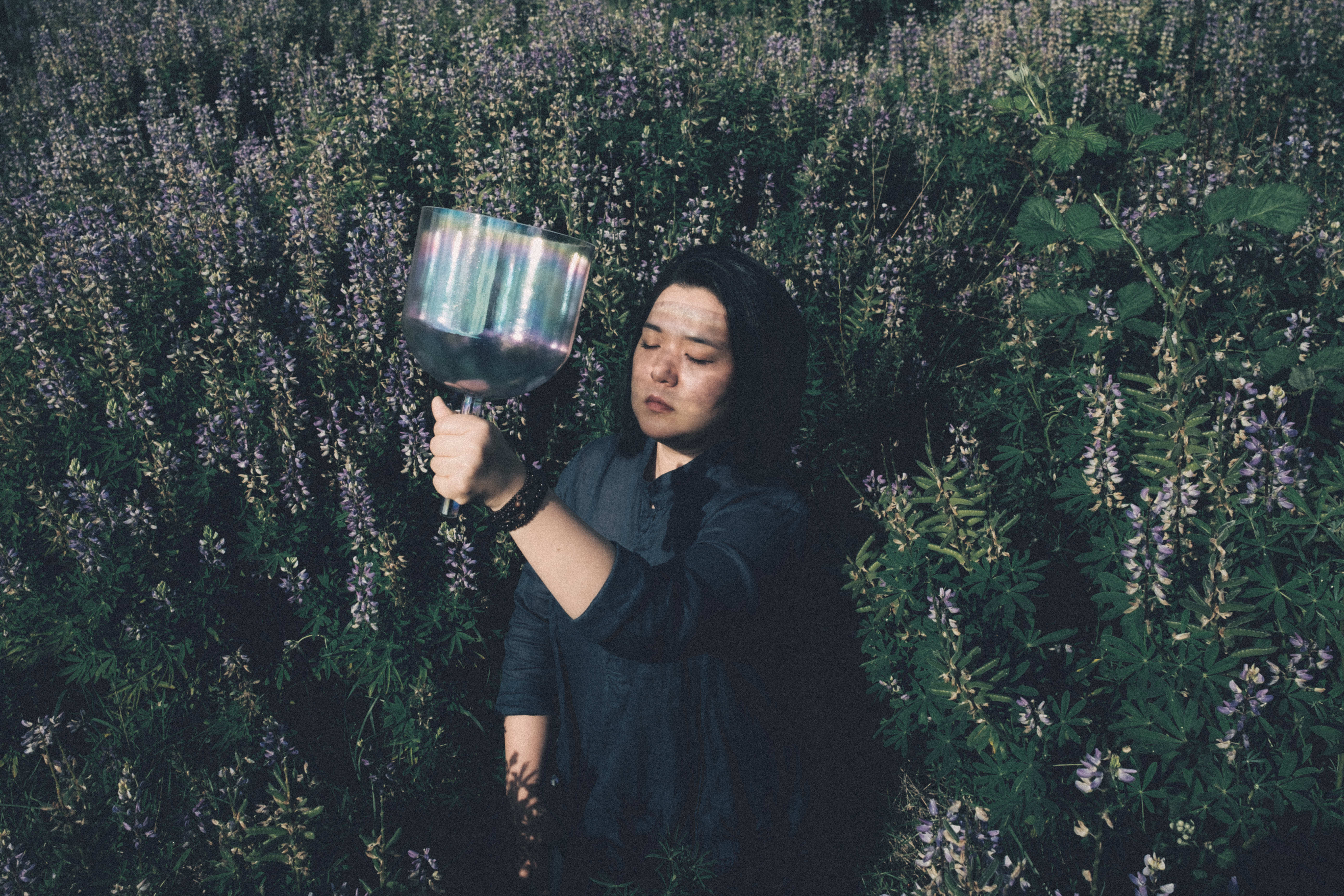 Seyeong holding a crystal singing bowl among wildflowers